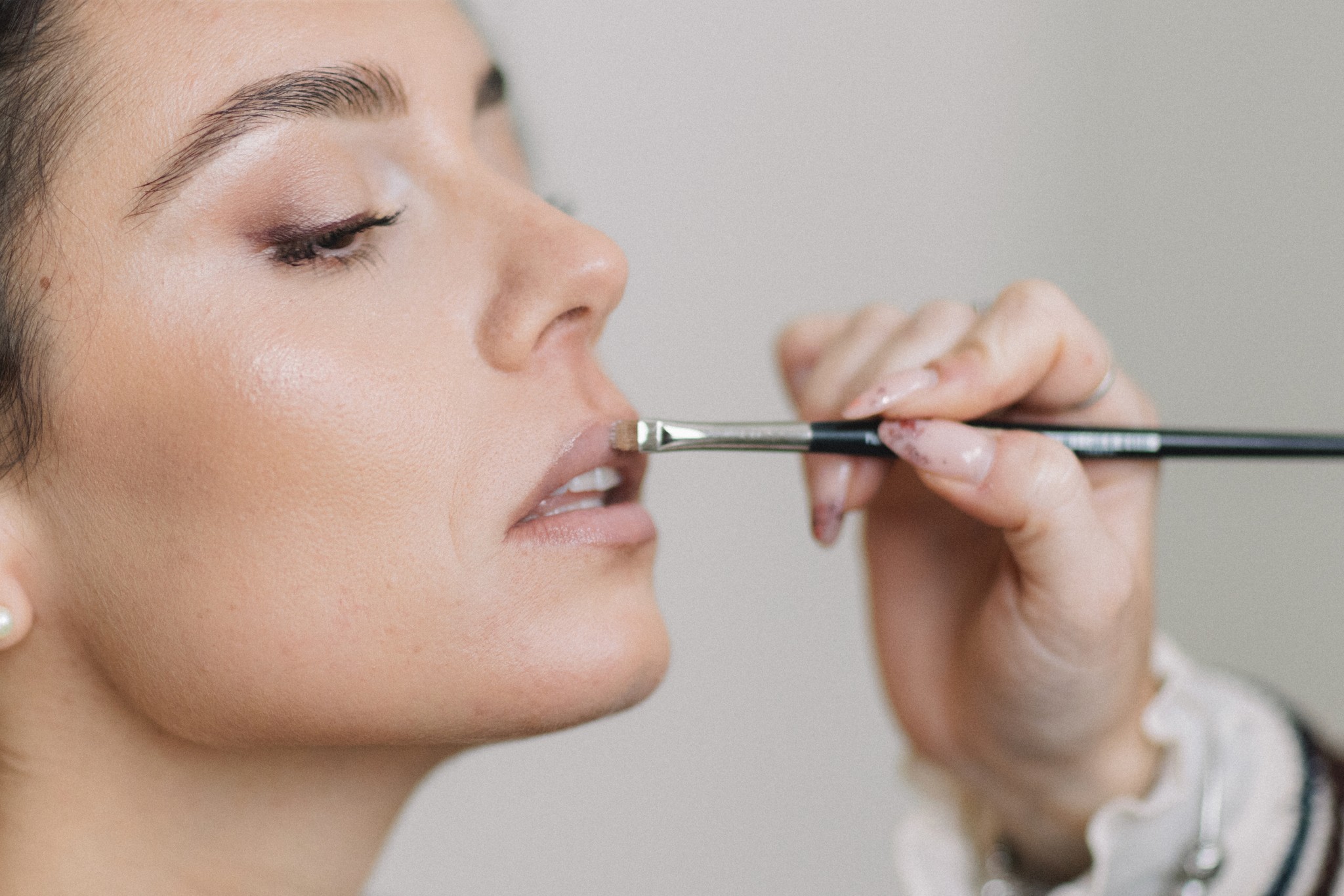 Sposa applica trucco durante i preparativi del matrimonio, dettaglio del volto in profilo con pennello per il make-up