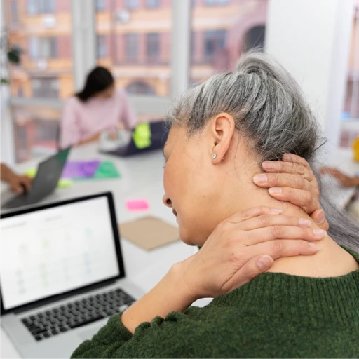 Woman in an office environment rubbing her neck in pain