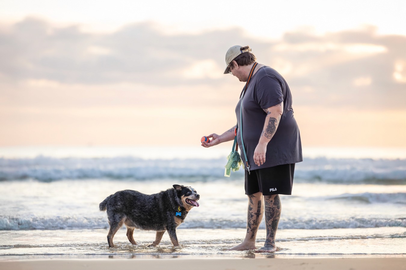 Blue heeler with his owner playing fetch at the beach