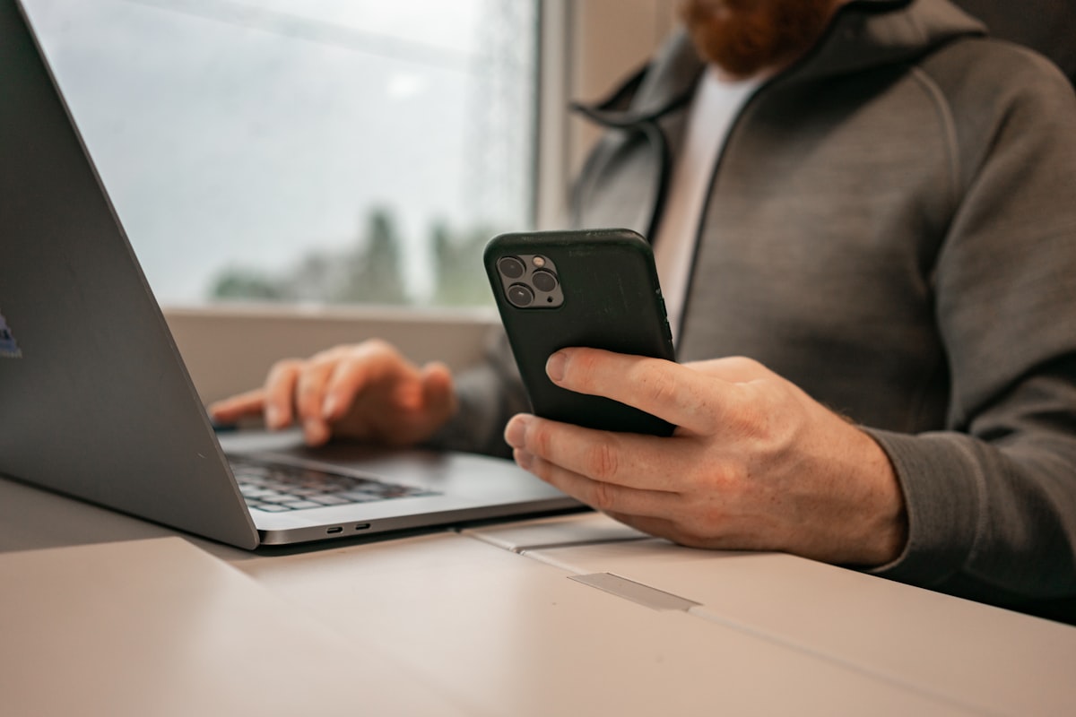 Person booking a trip on a laptop and phone with an AI travel agent