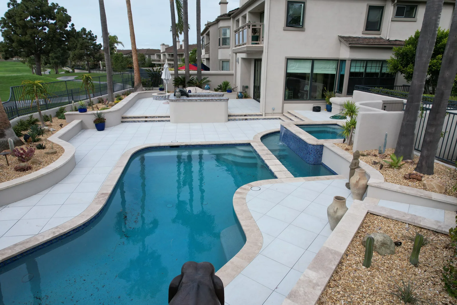 Aerial view of a curved pool, paved patio and raised spa