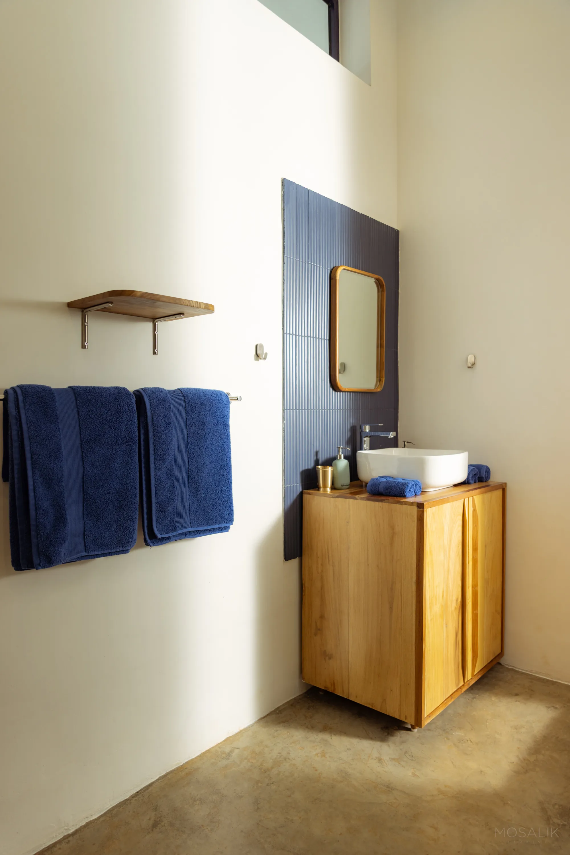Wooden vanity and navy towels in a Jaali Blue bathroom