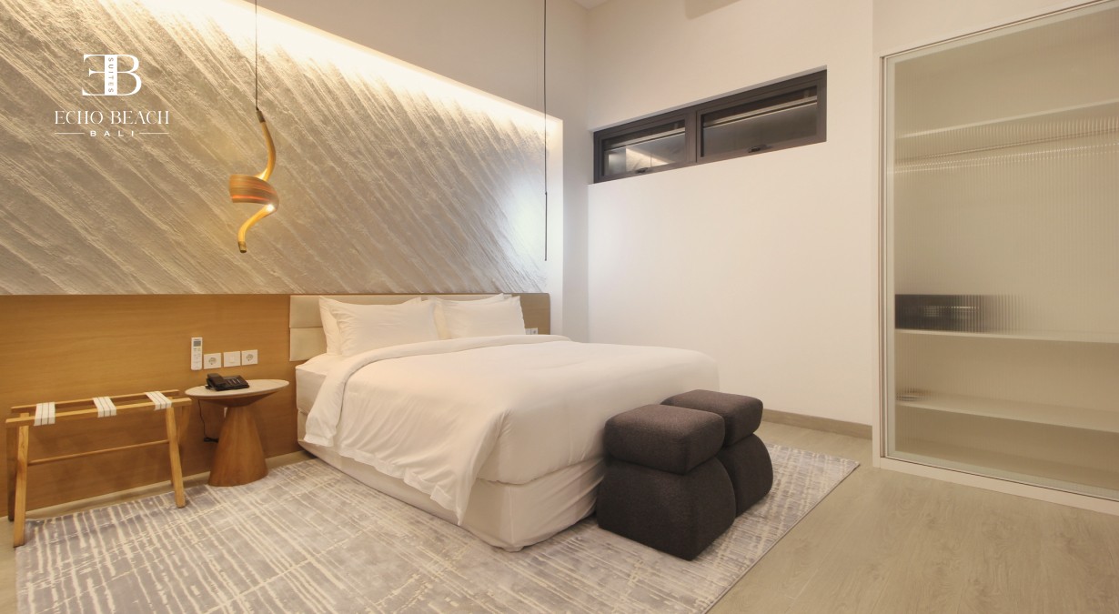 Stylish main bedroom with luggage rack, bedside table, and ambient lighting in the three bathroom Echo Beach Suite apartment in Canggu, Bali.