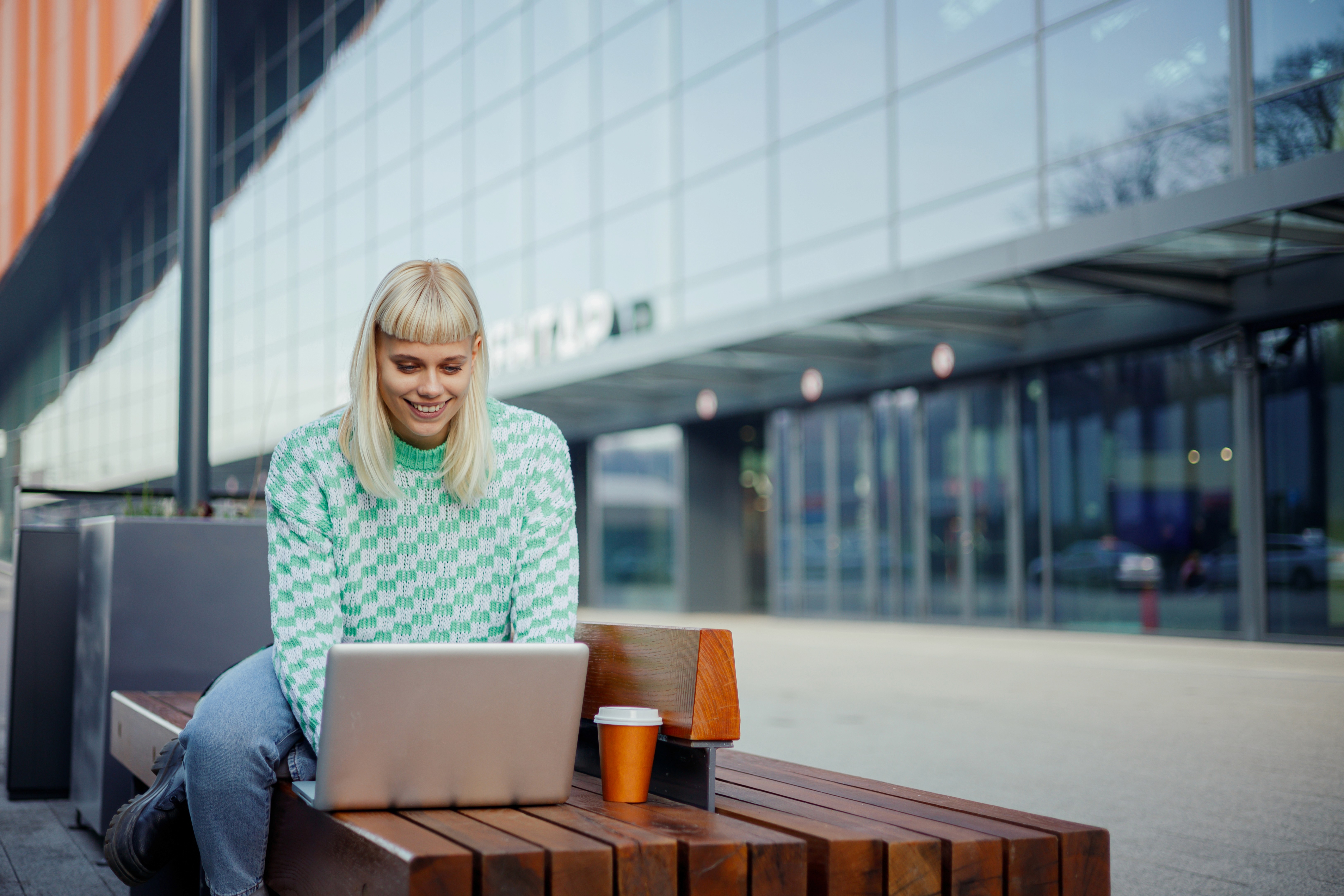 Older man in glasses sitting with laptop on coffee table, smiling while working.
