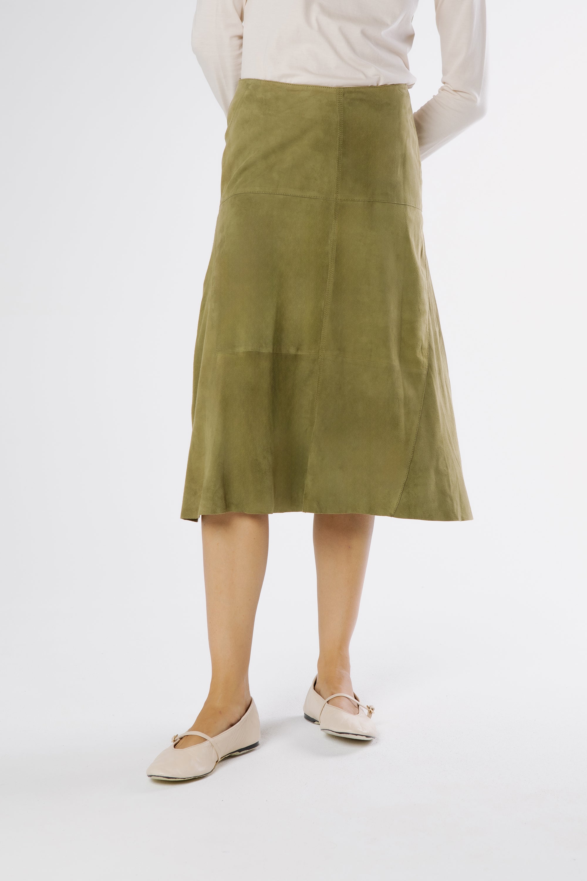 Side view of basil green suede midi skirt highlighting fluid drape and structured panels.