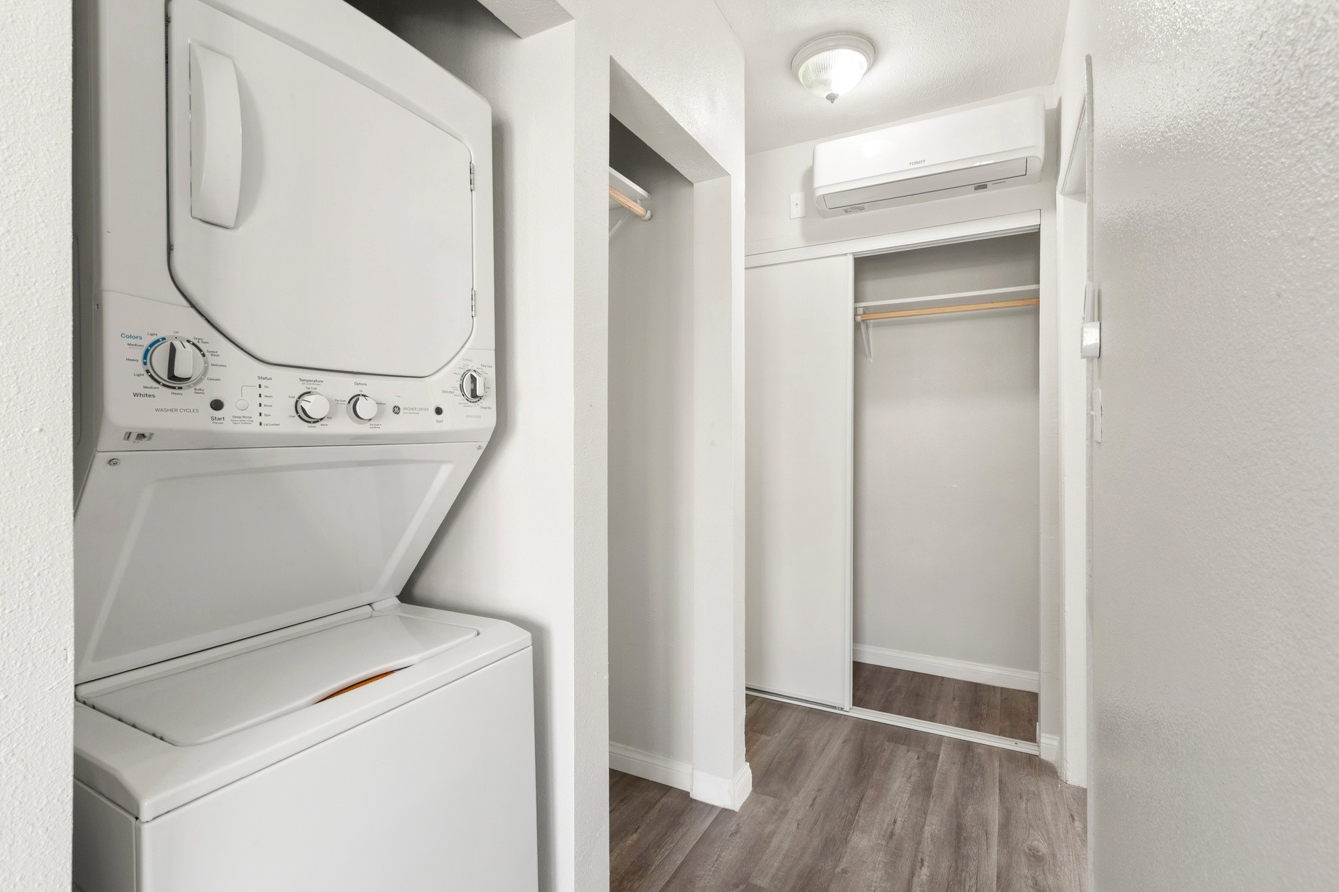 A bright laundry area at 4421 Wall, featuring a stacked washer and dryer, with a hallway leading to an open closet.