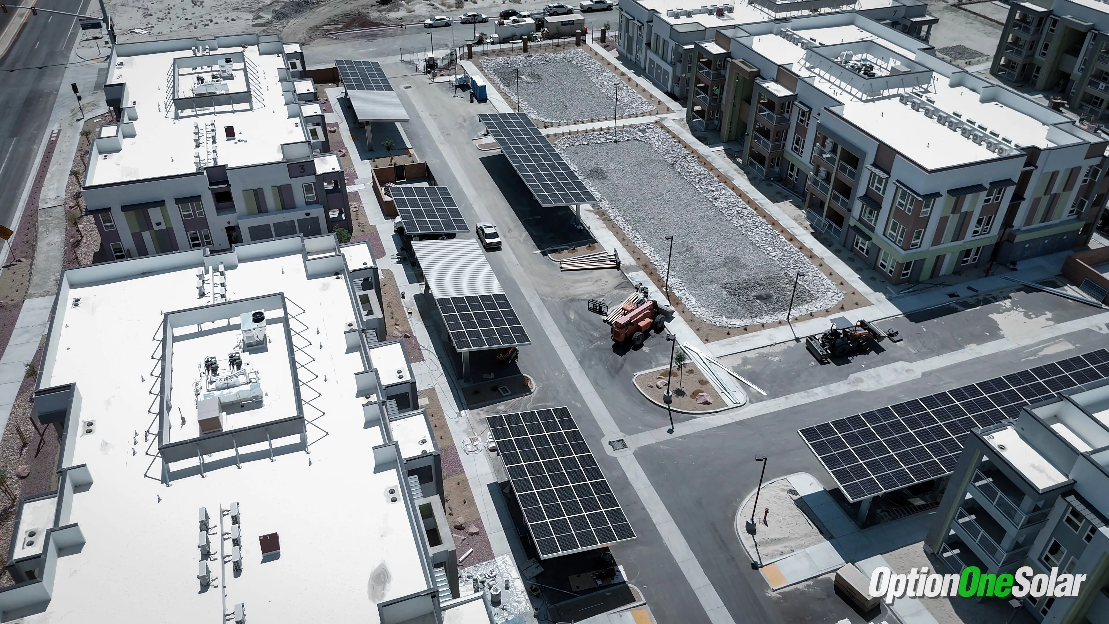 Aerial view of a new apartment complex with solar carports installed over parking areas, providing shade and clean energy.