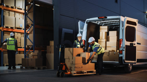 image of two people hand loading a LWB van with boxes at night
