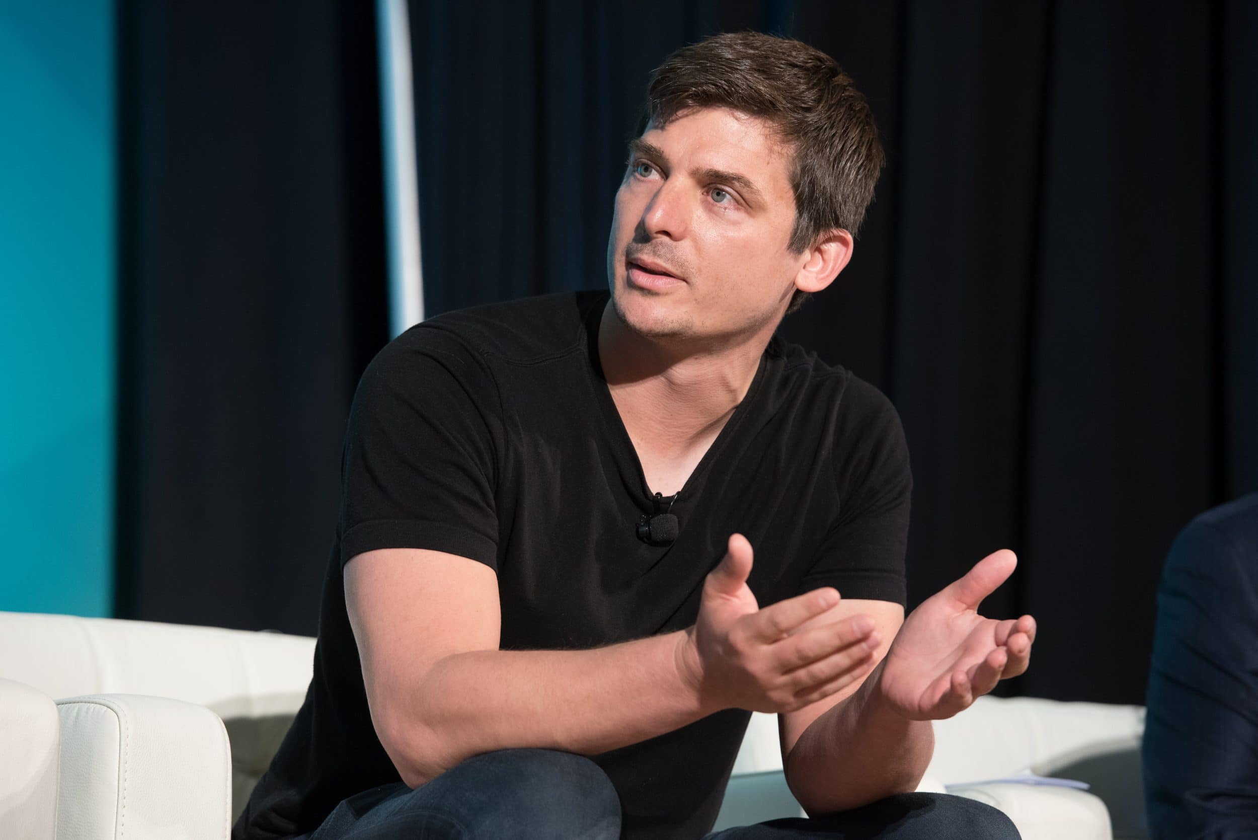 a white man talking on a panel looking to the left