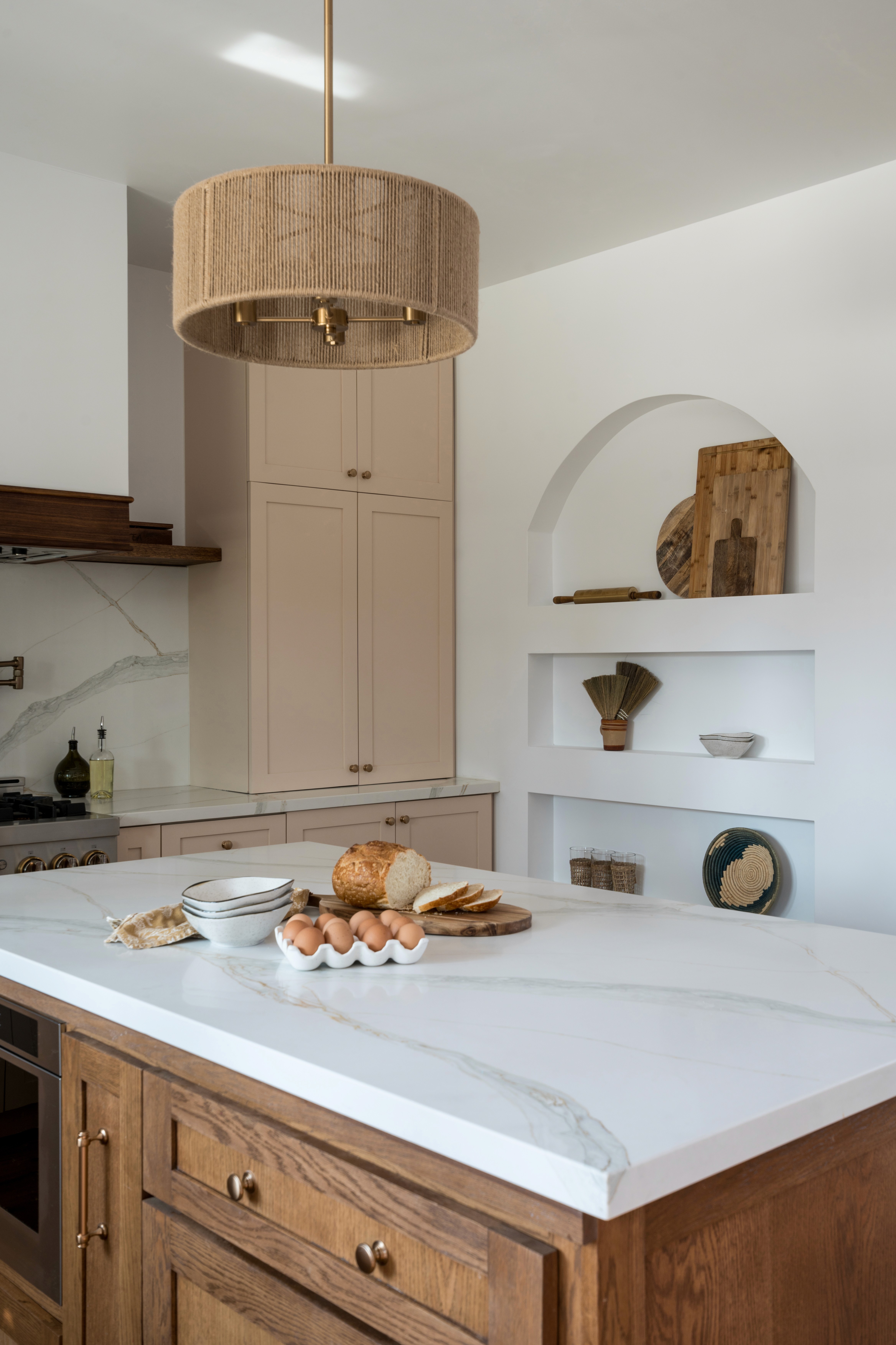 A bright and feminine kitchen featuring white countertops, soft pastel accents, and modern cabinetry. The space is designed with clean lines, a central island for gathering, and plenty of light, creating an inviting atmosphere by Jubilee Interiors in Lakewood, California