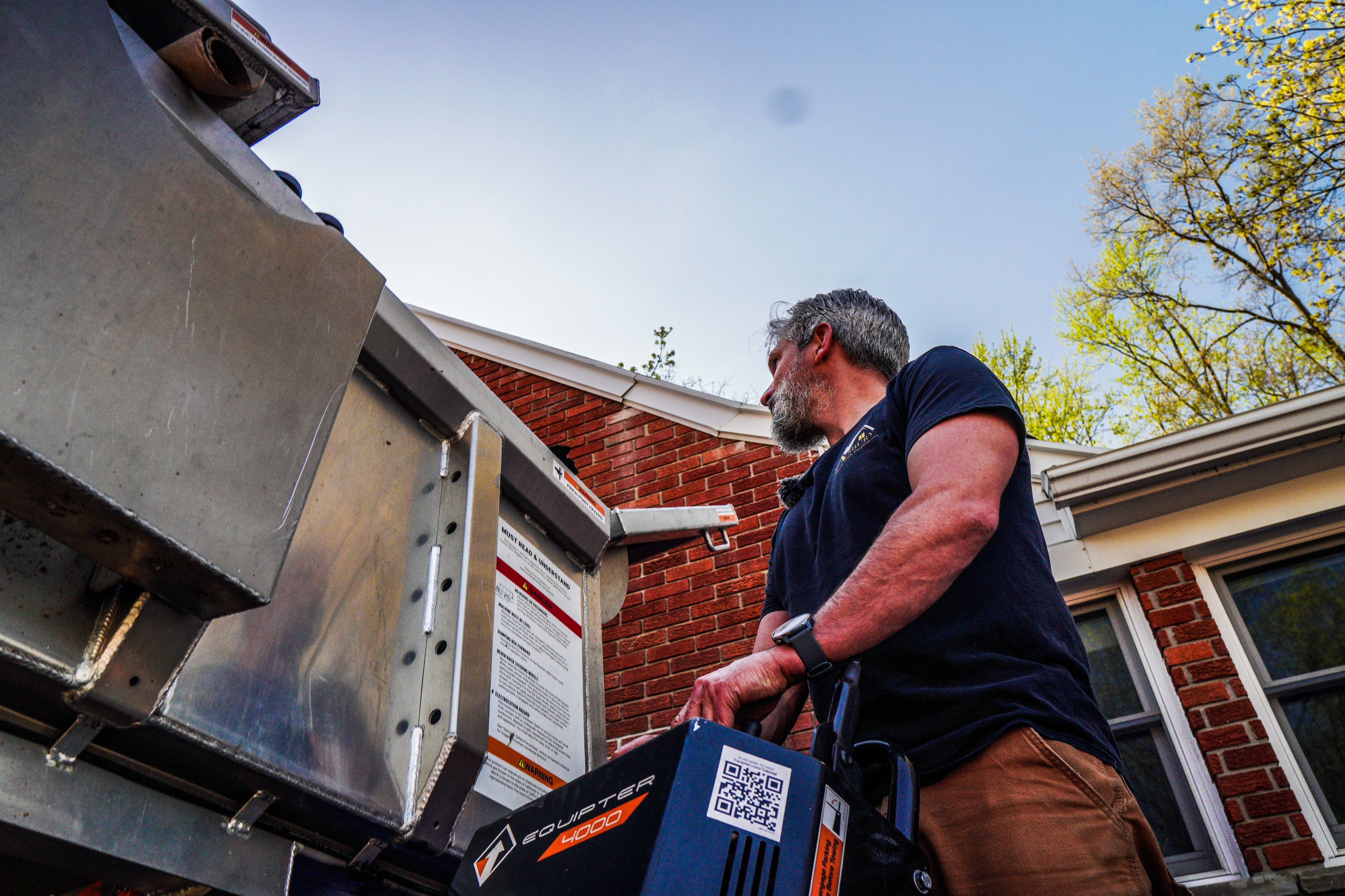 Asbury team member unloading equipment beside a brick home