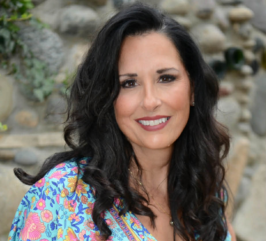 Image of a woman wtih black hair and a flower top with a nature background