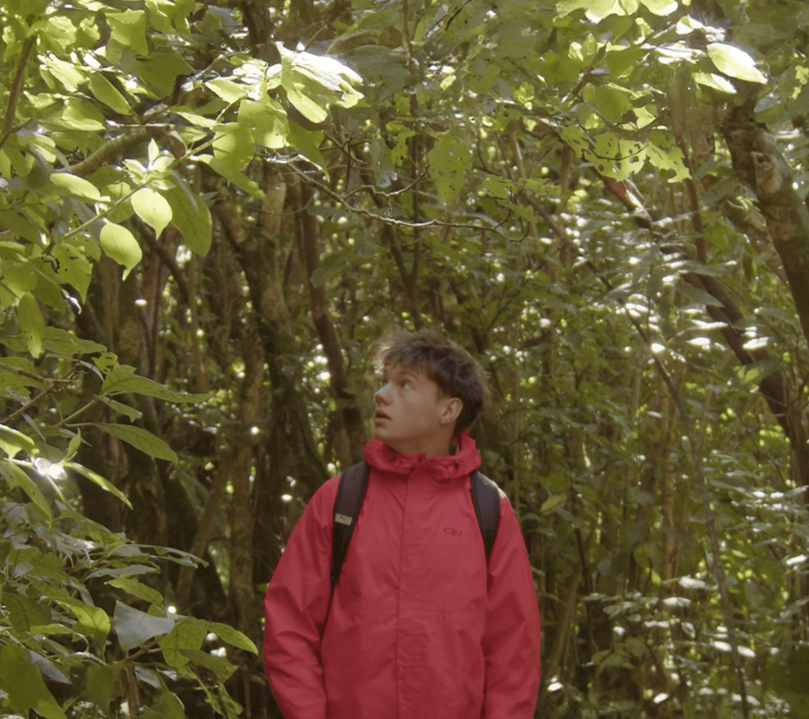 A thoughtful young person with dark hair gazes to the side, captured in soft black and white lighting.