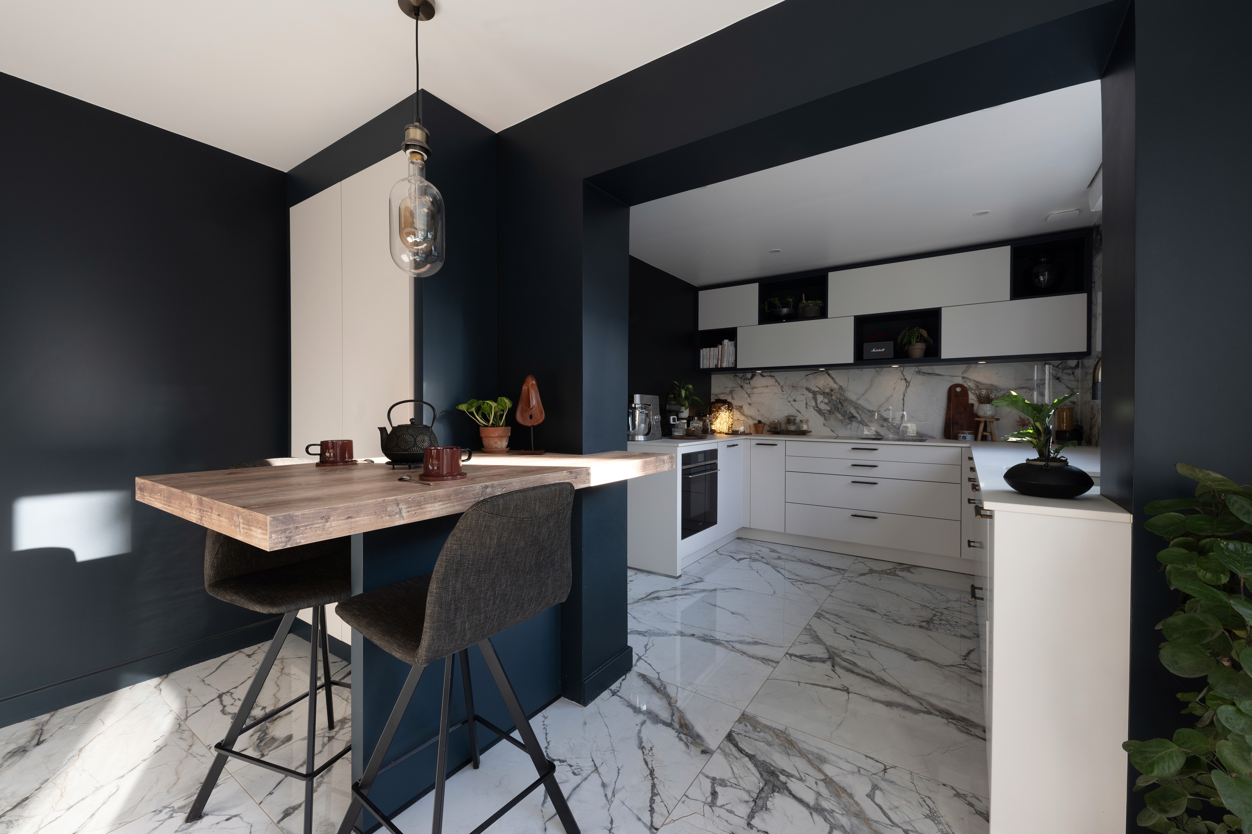 Rénovation douche minimaliste 77 avec grand pommeau plafond, murs pierre texturée et carrelage gris clair, architecte d'intérieur clé en main.