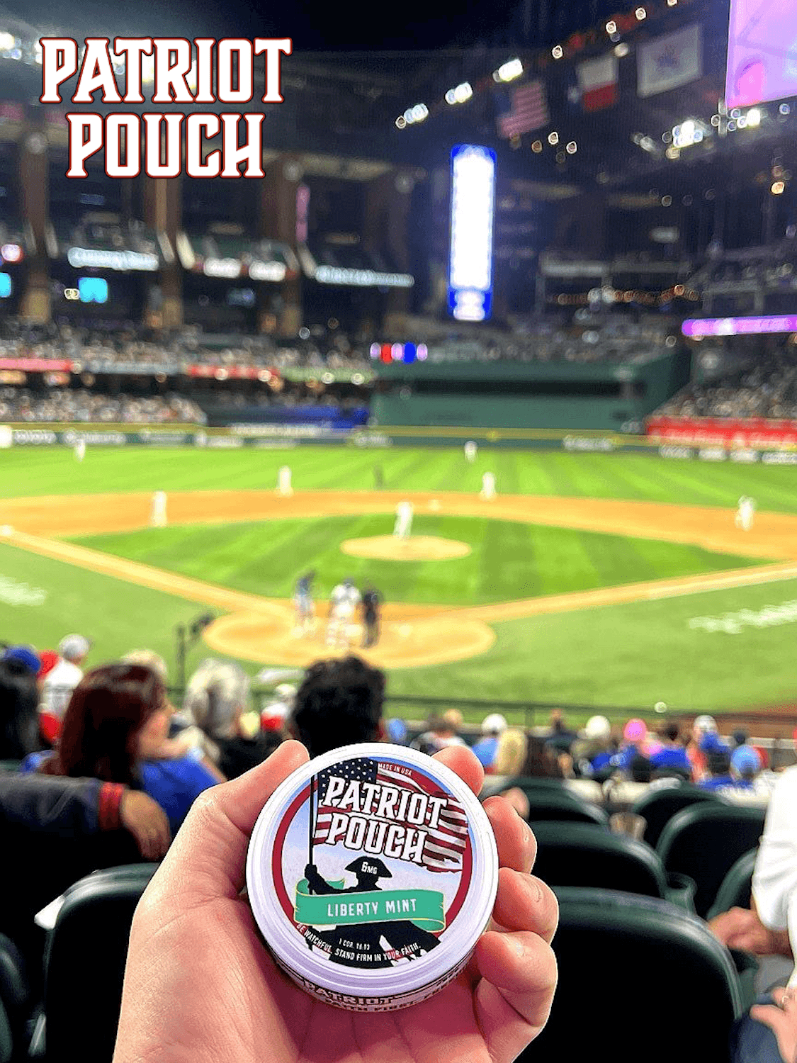 Hand holding Patriot Pouch Liberty Mint can at a baseball stadium during a nighttime game.