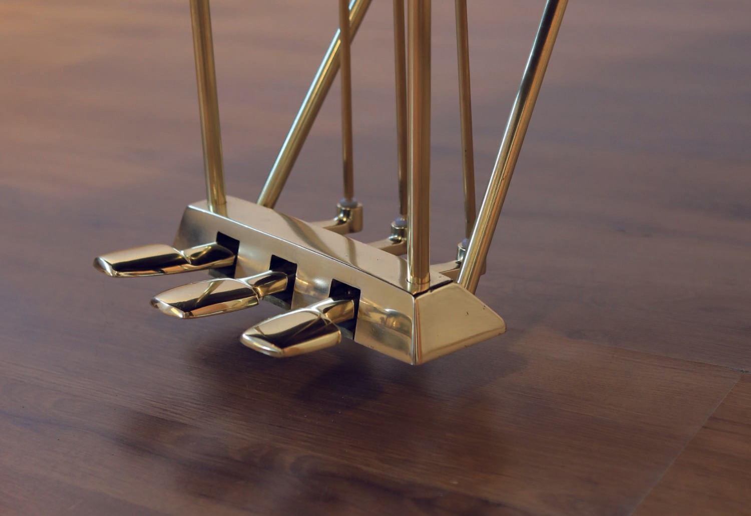 A detailed shot of the polished brass pedals, reflecting the luxurious finishing touches of the restored piano.