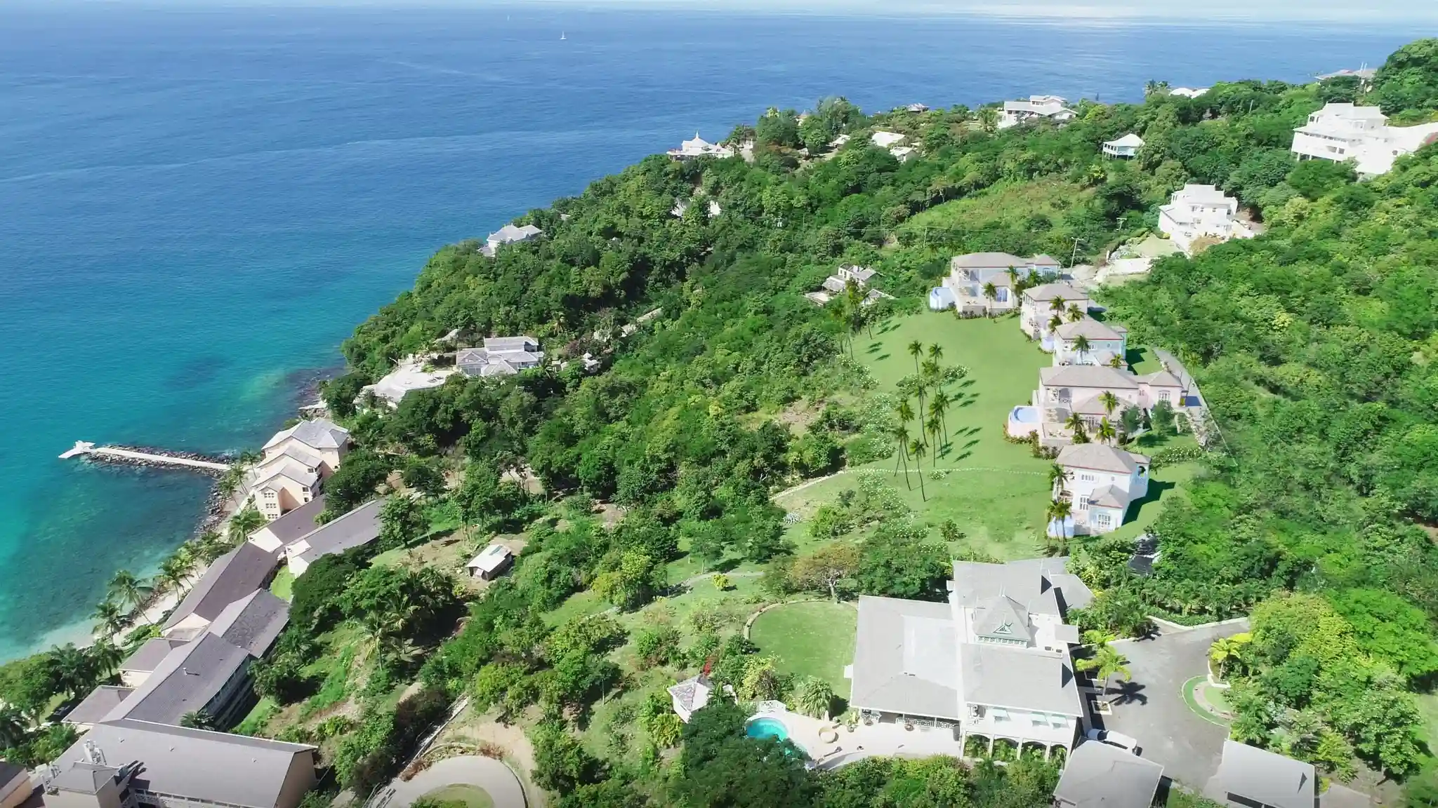 Aerial view of a Caribbean coastal resort by Atelier International — multi-villa hospitality development with private villas, lush hillside landscape, and oceanfront access.