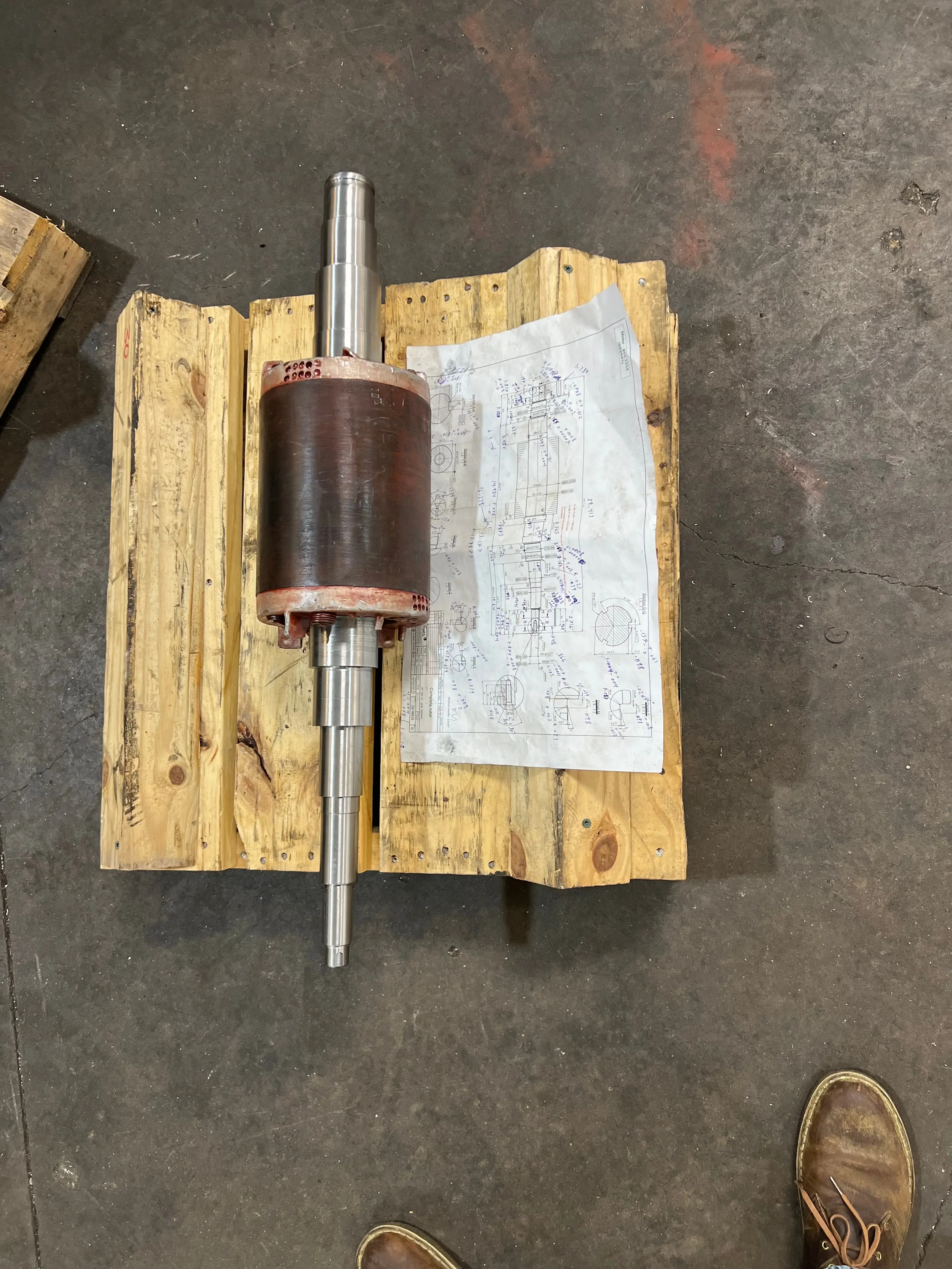Man with tousled hair sitting at a cluttered desk in a dimly lit room. Warm, orange lighting creates a moody and contemplative atmosphere.