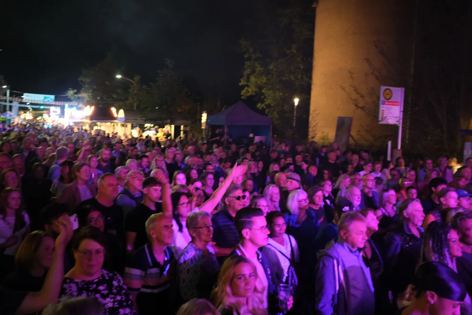 Dichtes Publikum bei Nacht, warmes Licht von der Bühne.