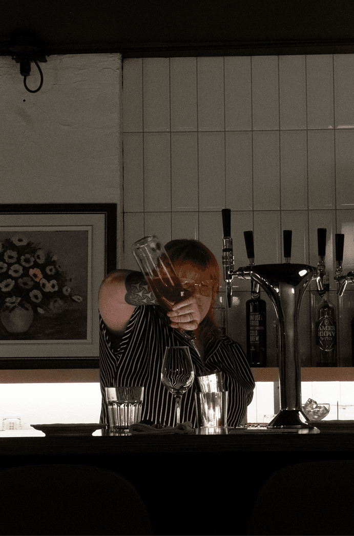 La barmaid du Saison prépare un cocktail derrière le bar.
