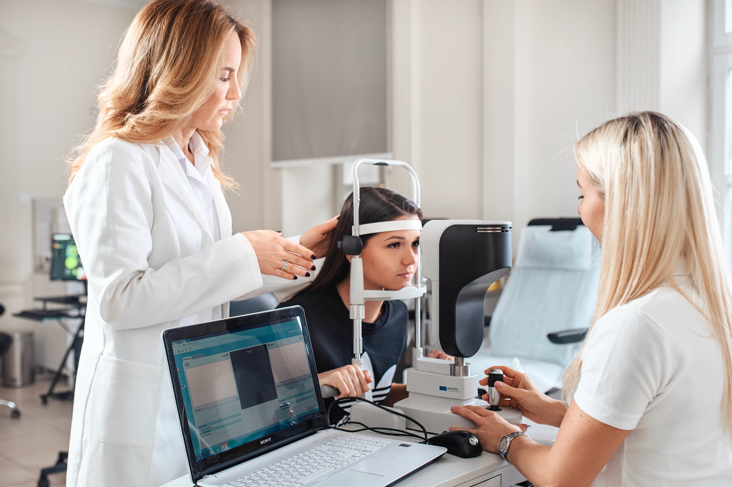 Patient undergoing an eye exam with assistance from a doctor in a modern clinic