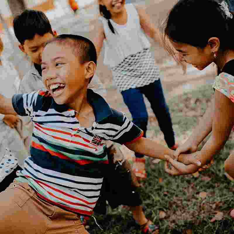Phot of children playing in a playground together smiling.