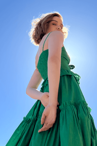 Young woman wearing a green dress. Blue sky. Low angle camera.