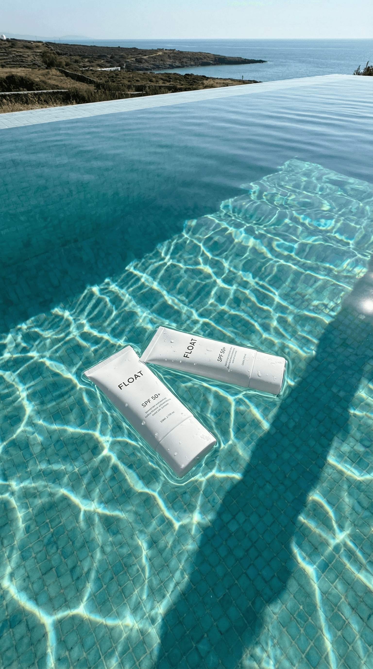 Float SPF 50+ sunscreen tubes floating in infinity pool with ocean view