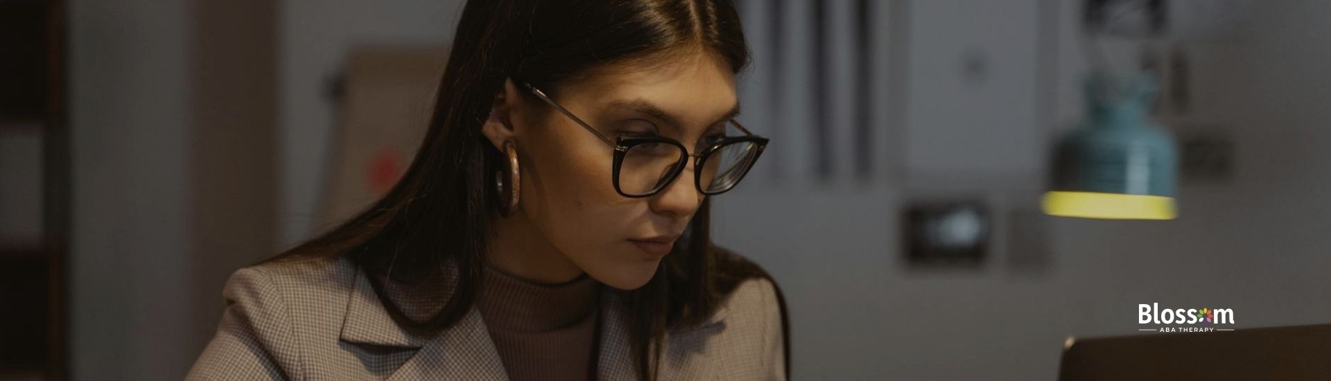 An aspiring RBT in glasses fully concentrating on her study for RBT exam at a desk in Maryland.