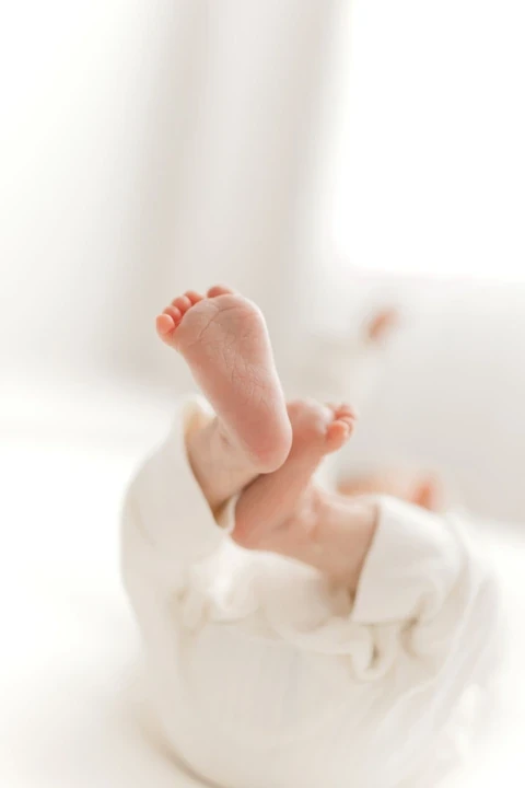 Baby feet raised above a white outfit