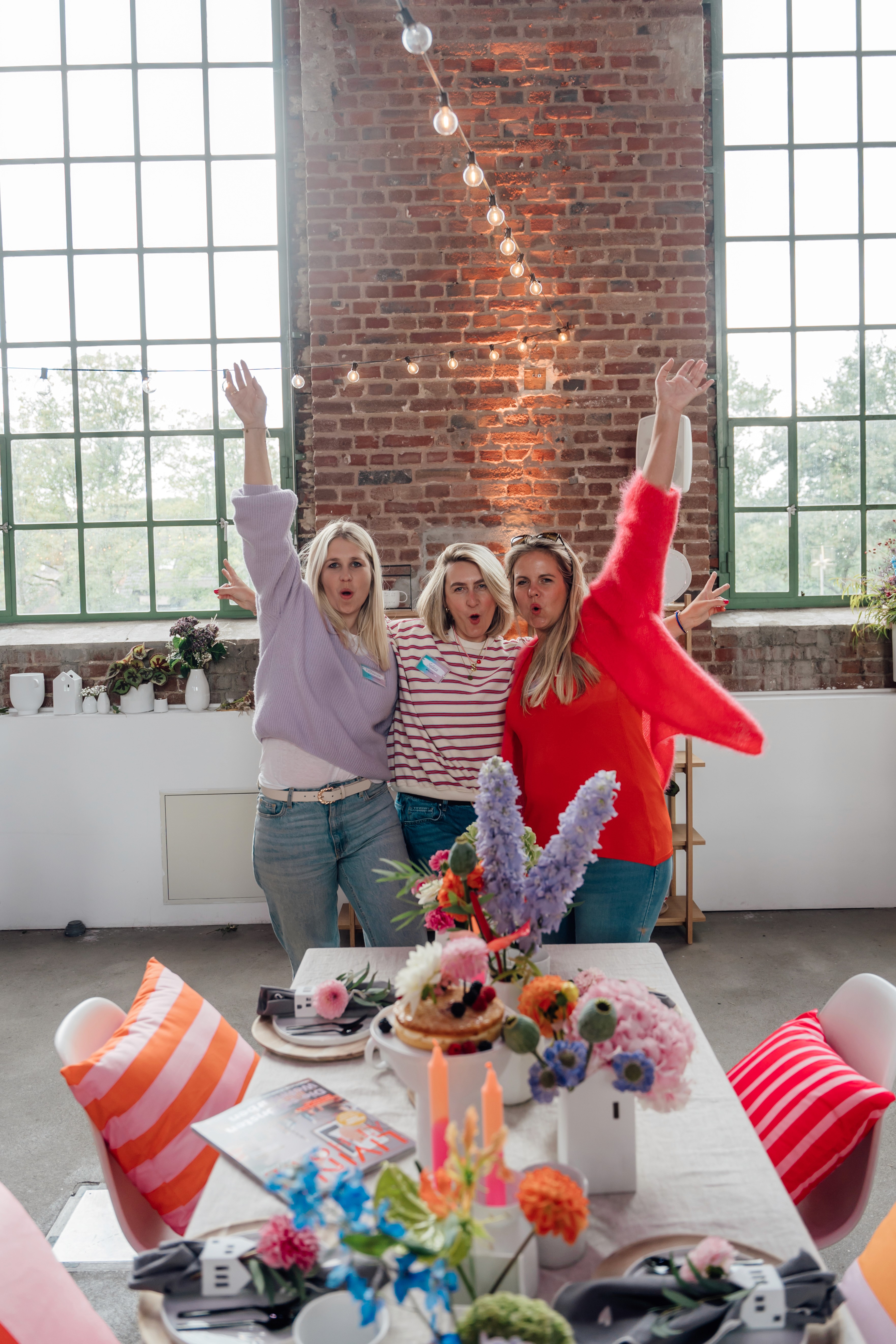 Drei Frauen jubeln gemeinsam bei einem Kreativ-Workshop mit raeder in einer lichtdurchfluteten Eventlocation