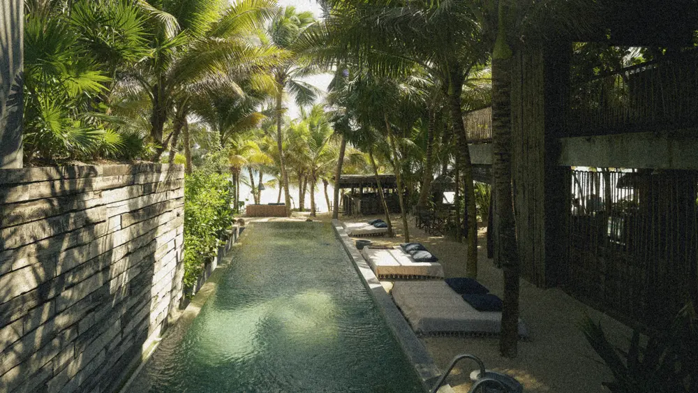 Pool area surrounded by jungle ambiance with loungers and tranquility at Be Tulum.