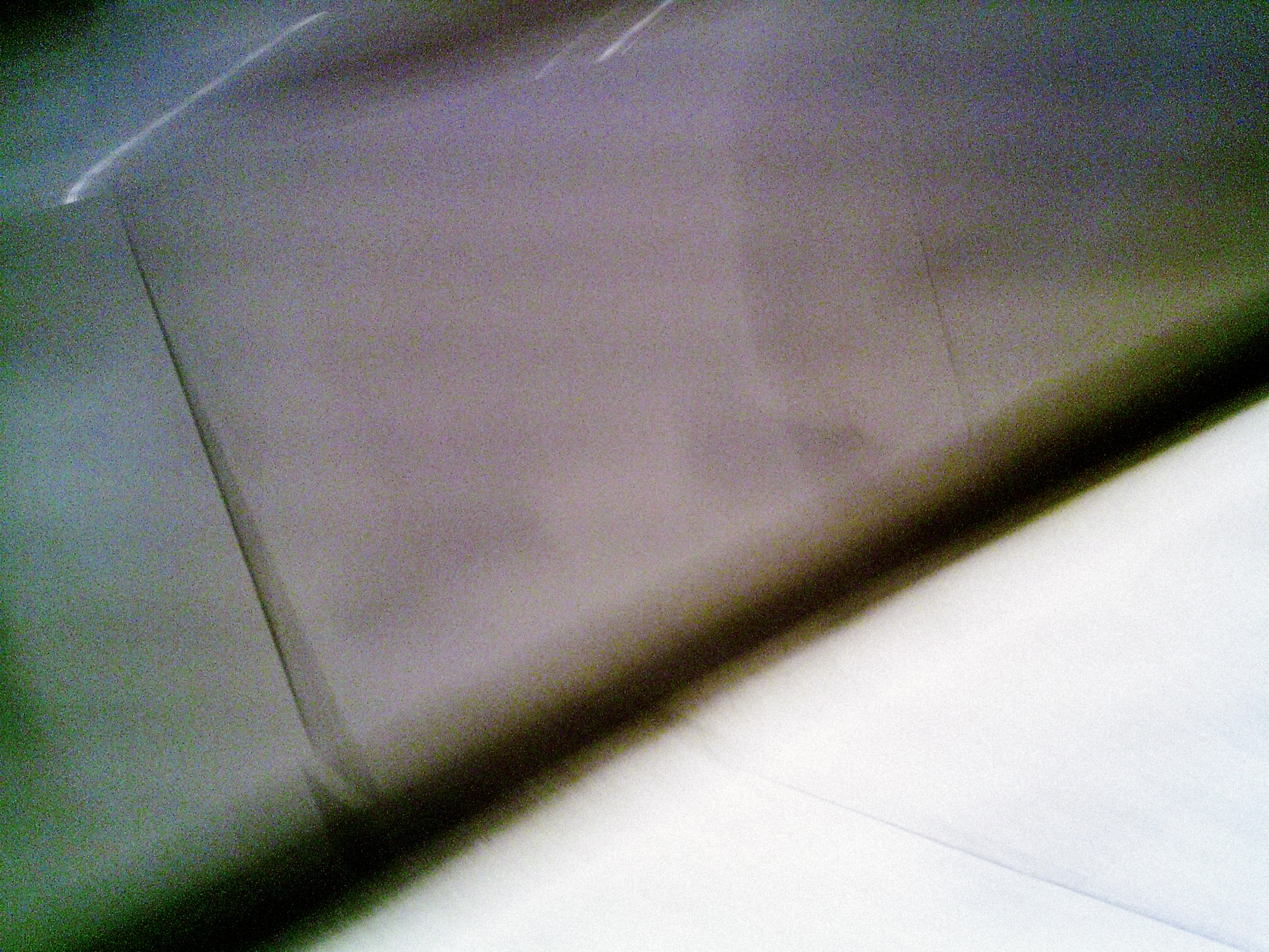 Severe defocus and color shift create abstract composition of grey diagonal form against white