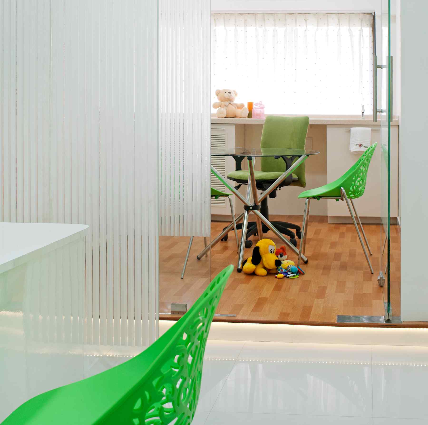 Nature-inspired preschool entrance with sculptural tree partitions and suspended green leaf ceiling panels.