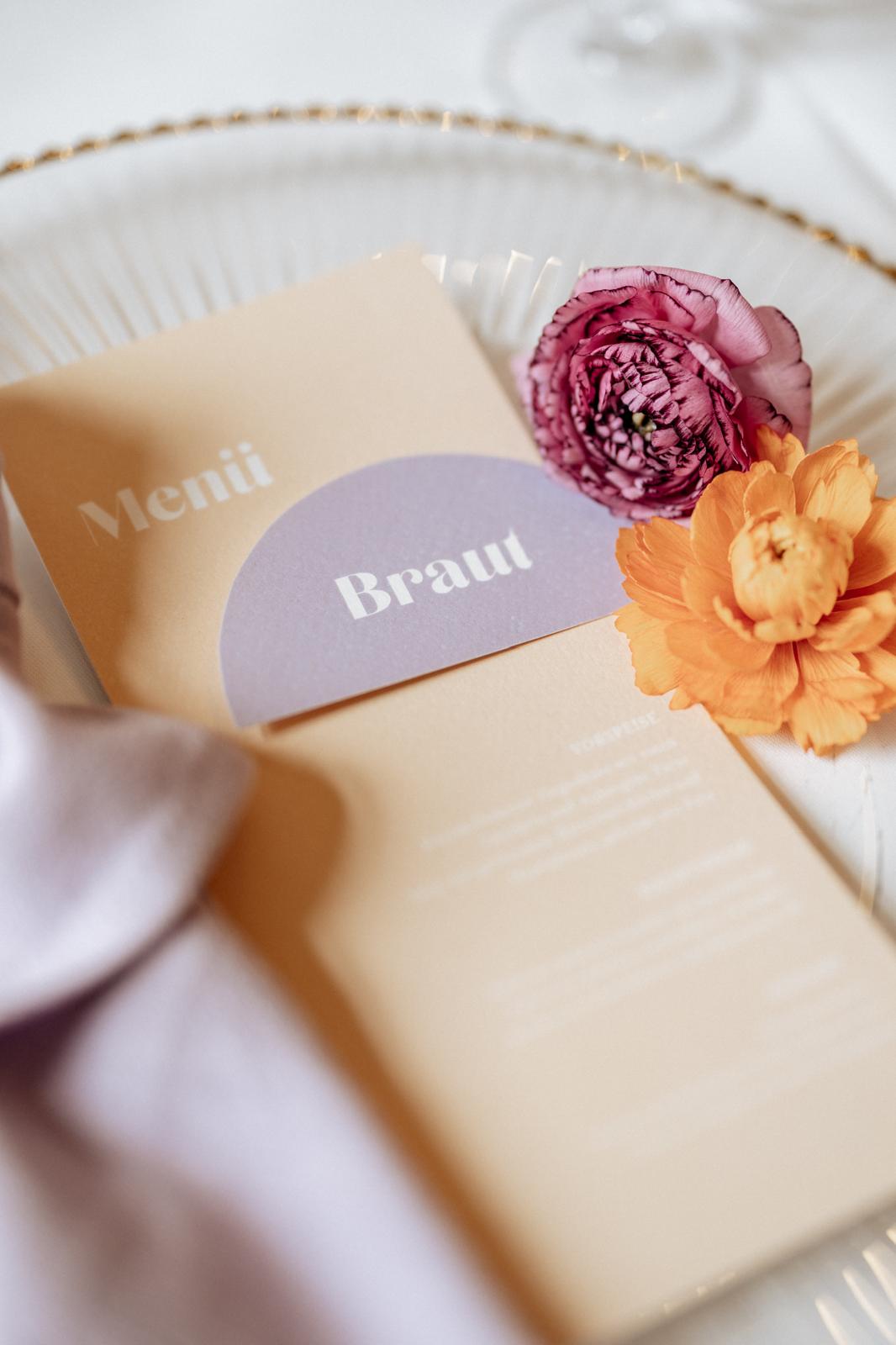 Detailaufnahme einer stilvollen Menükarte mit floraler Hochzeitsdekoration