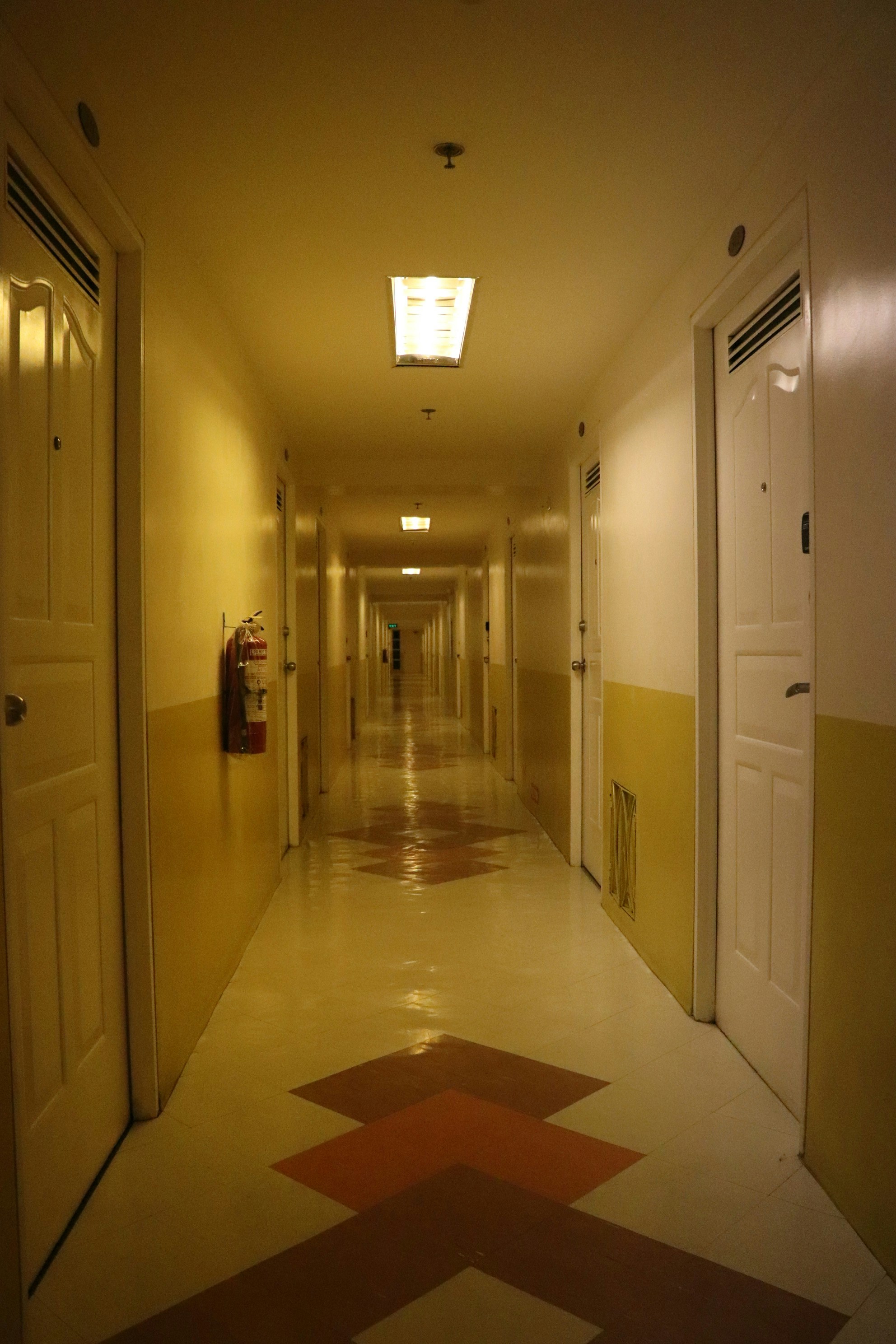 a long hallway with yellow walls and red and white flooring