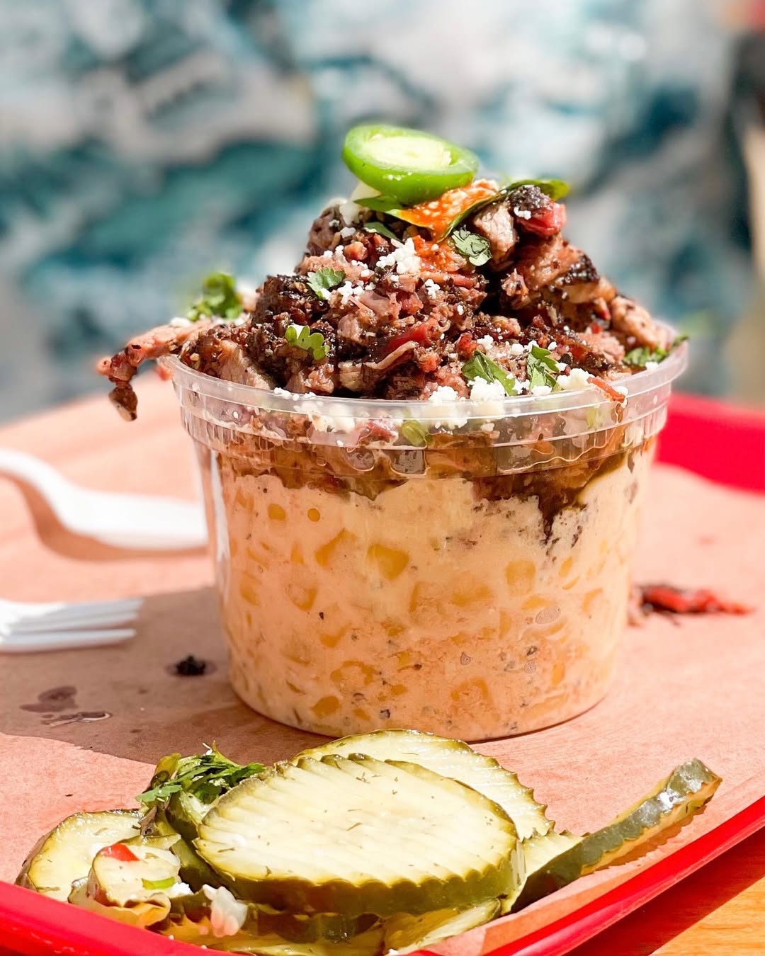 A festive platter of roasted vegetables, including sliced, seared pears or apples and charred tomatoes, garnished with walnuts and rosemary sprigs, set next to a pumpkin, a glass of red wine, and lit candles for a holiday or autumn meal.