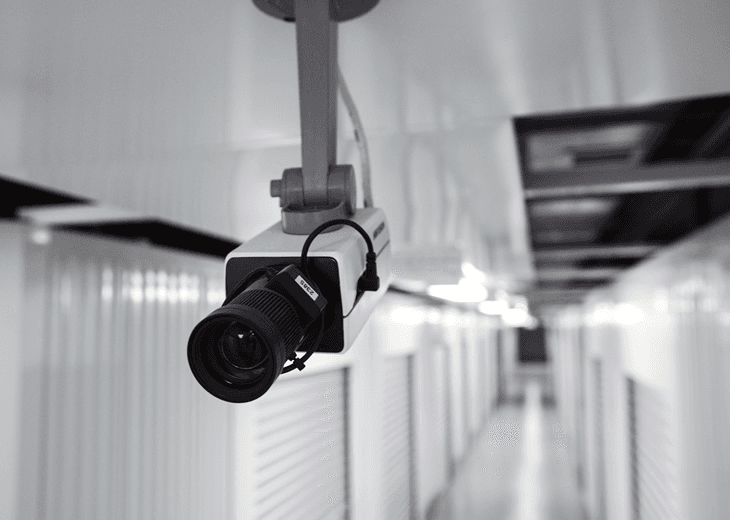 Surveillance camera monitors corridor for 24/7 security in trusted car storage facility.