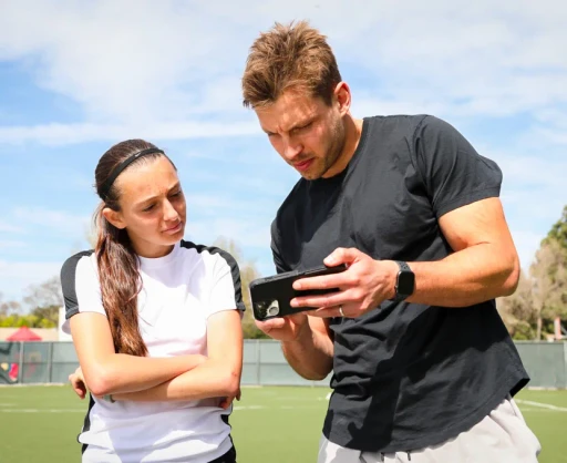 Soccer coach reviewing game footage with a young player on a smartphone, demonstrating Reeplayer’s mobile app for in-depth game analysis