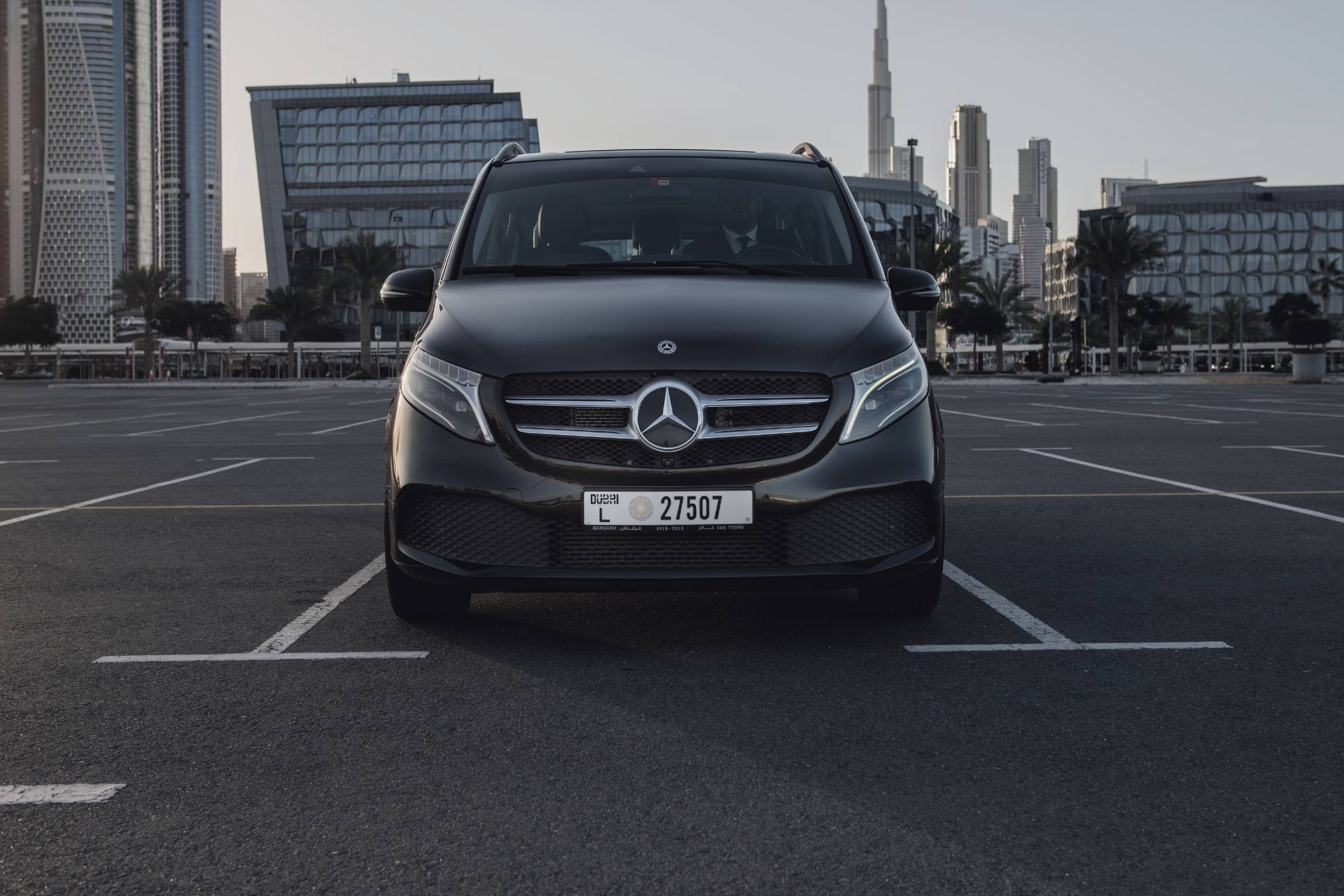 black mercedes benz v class in a parking lot with the dubai skyline in the background