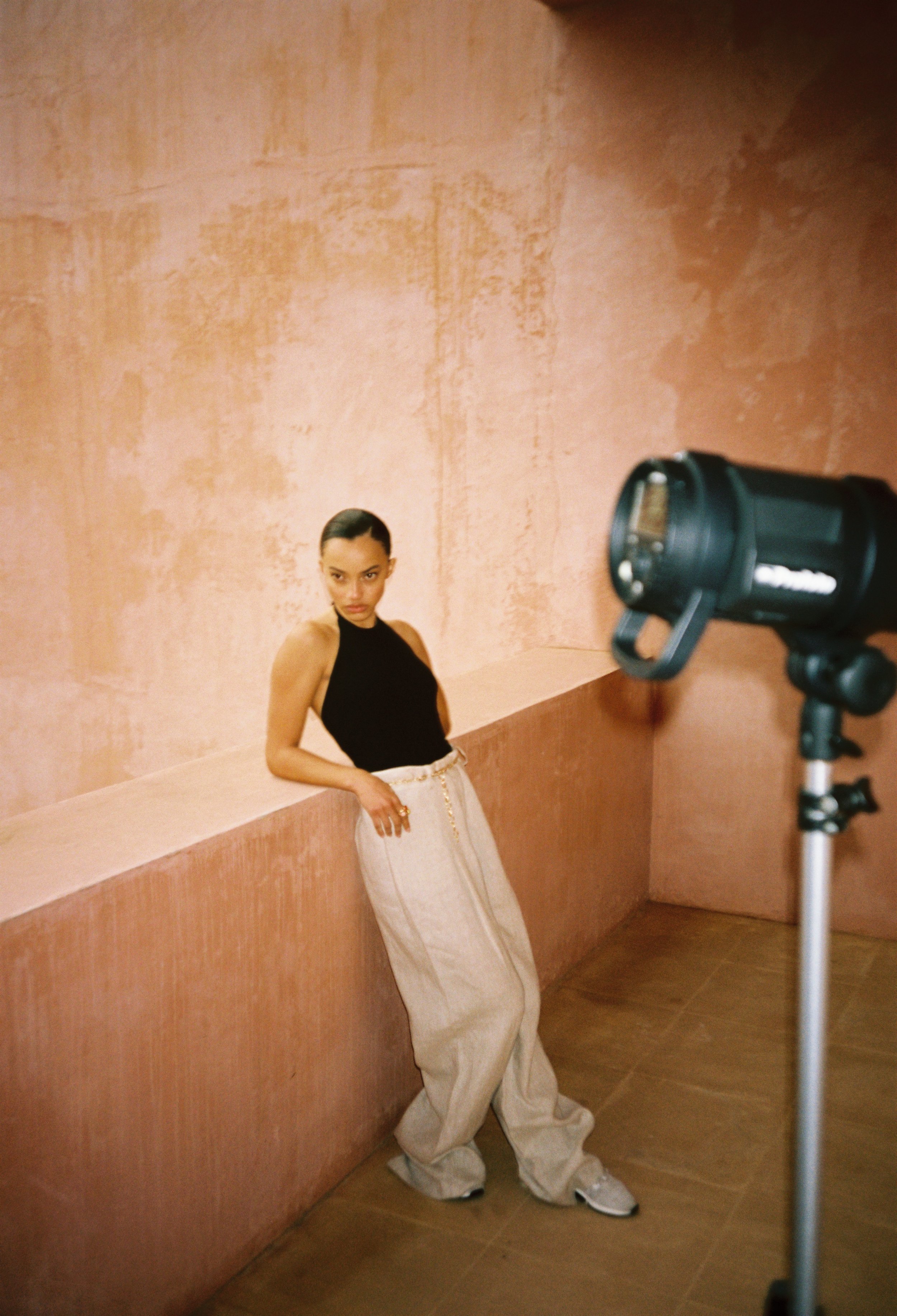 Odalisque editorial behind the scenes, portrait against a peach wall