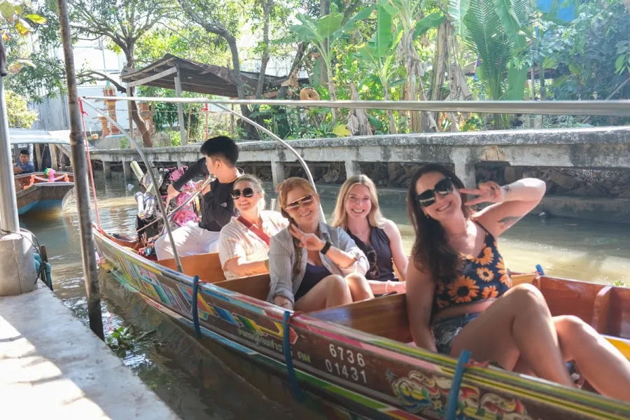 Group of women smiling aboard a traditional longtail boat on a Bangkok canal
