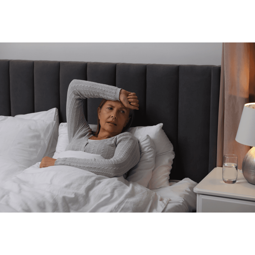 Woman in bed, holding her arm up, awake