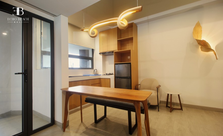 Modern kitchenette and dining area with a wooden table in the 1 BR Mezzanine apartment suite at Echo Beach, Canggu, Bali.