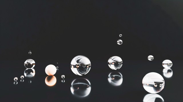 Sphères métalliques réfléchissantes de différentes tailles flottant sur fond noir.