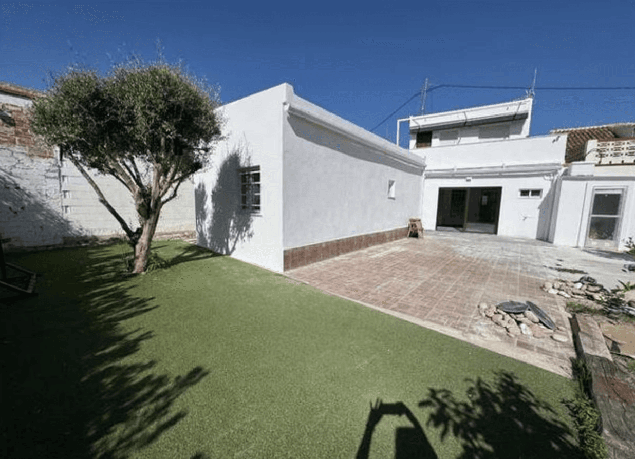 A modern brick house with a two-car garage, well-manicured lawn, and clear blue sky in the background.