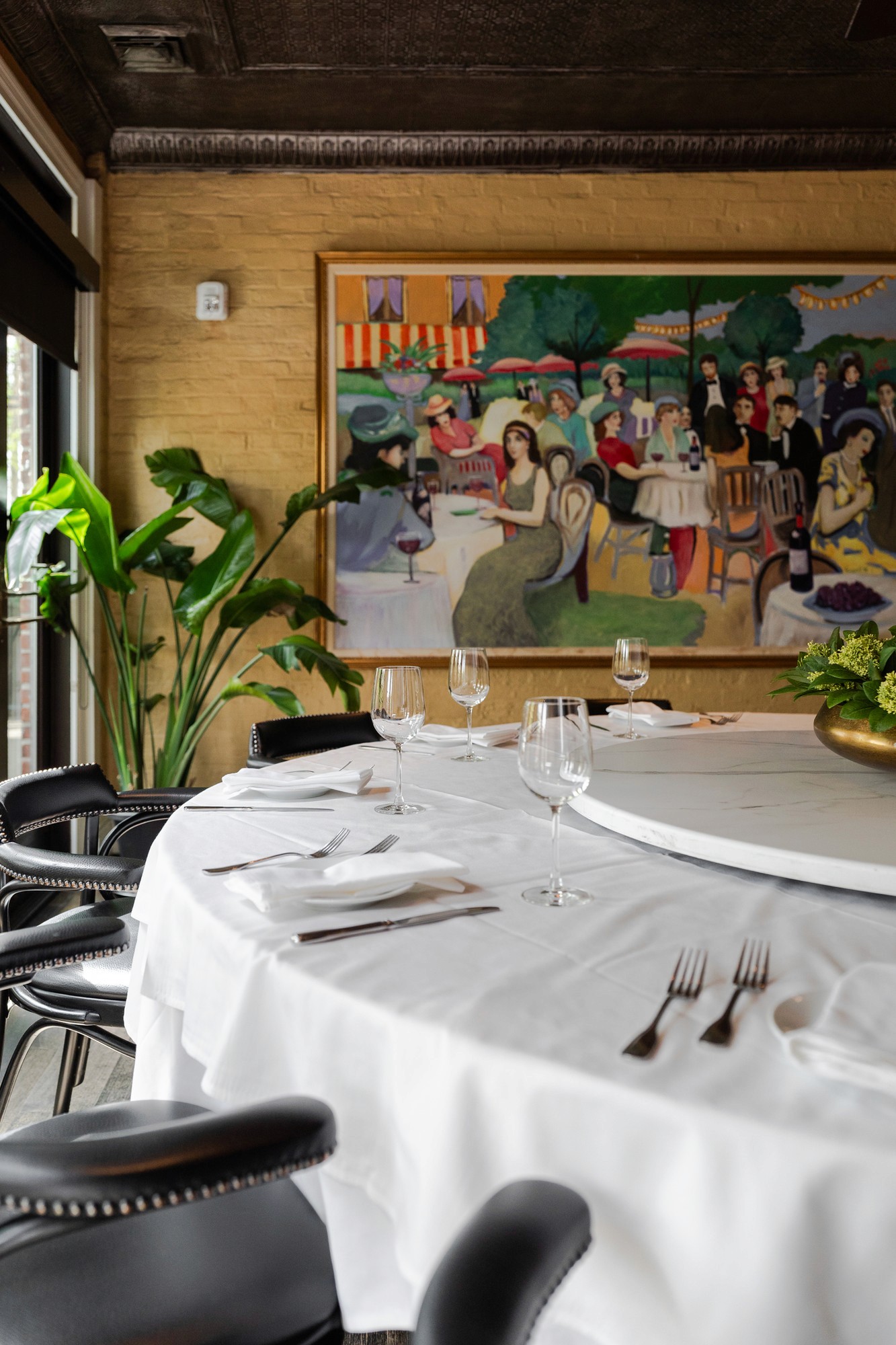 Round table with a white cloth and lazy Susan under a painting in the Terrace Room at Lindey's