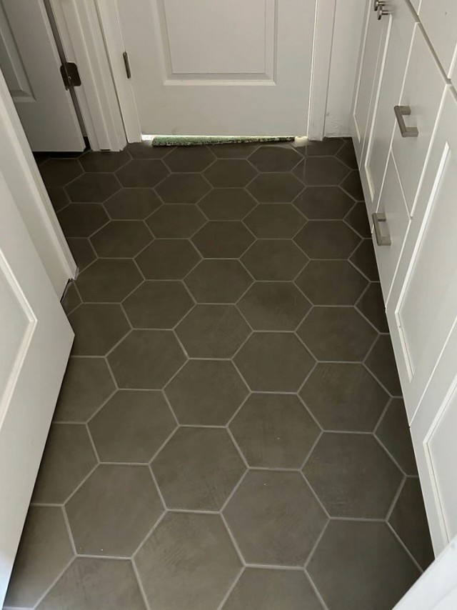 Modern hallway with gray hexagonal tile flooring and white cabinetry in a new home under construction.