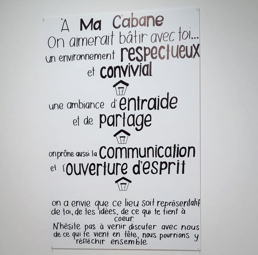 Panneau écrit à la main présentant les valeurs de Macabane : respect, convivialité, entraide, partage, communication et ouverture d’esprit.