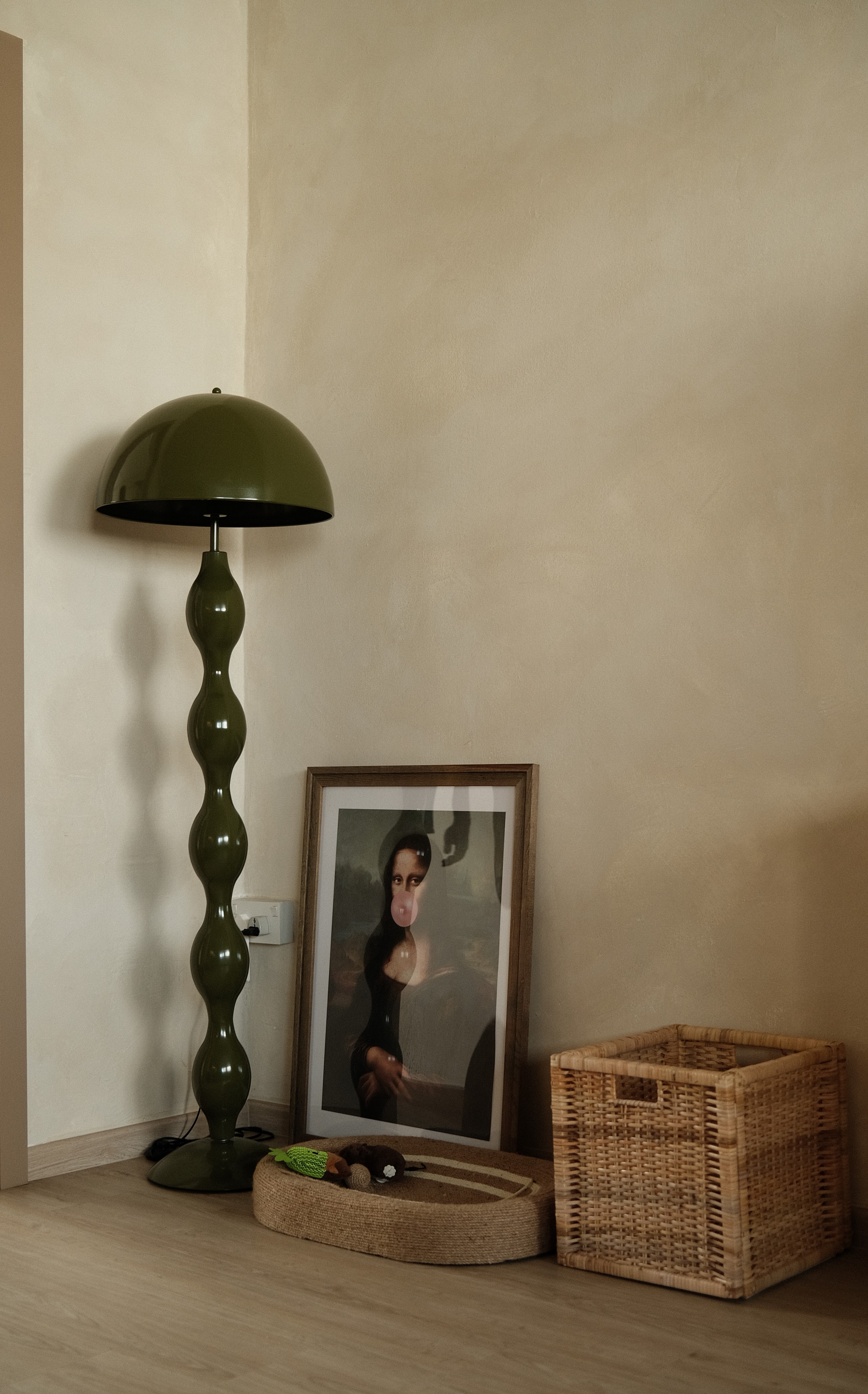 Corner vignette with vintage green lamp, framed photograph, and textured plaster wall. Cozy and eclectic touch in a modern living space.